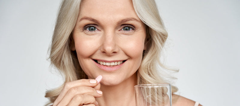 healthy woman with long grey hair taking a supplement