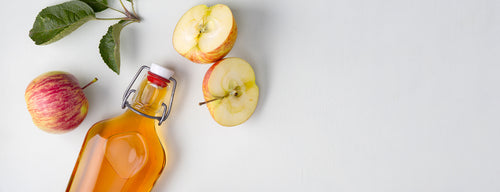 glass bottle of apple cider vinegar with apples