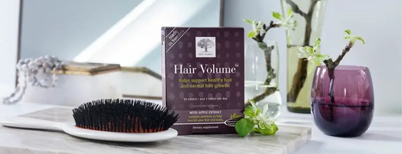 pack of New Nordic Hair Volume Tablets with a hairbrush and fresh plants