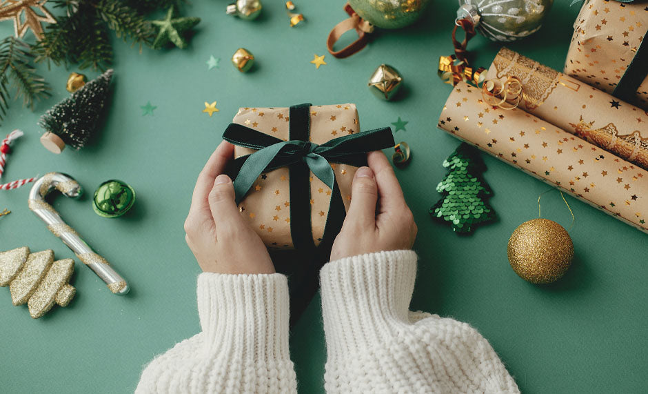 beautifully wrapped gift with velvet green ribbon with Christmas decorations in green and gold