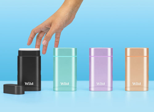 colourful aluminium deodorants on a blue background with a hand about to pick one up
