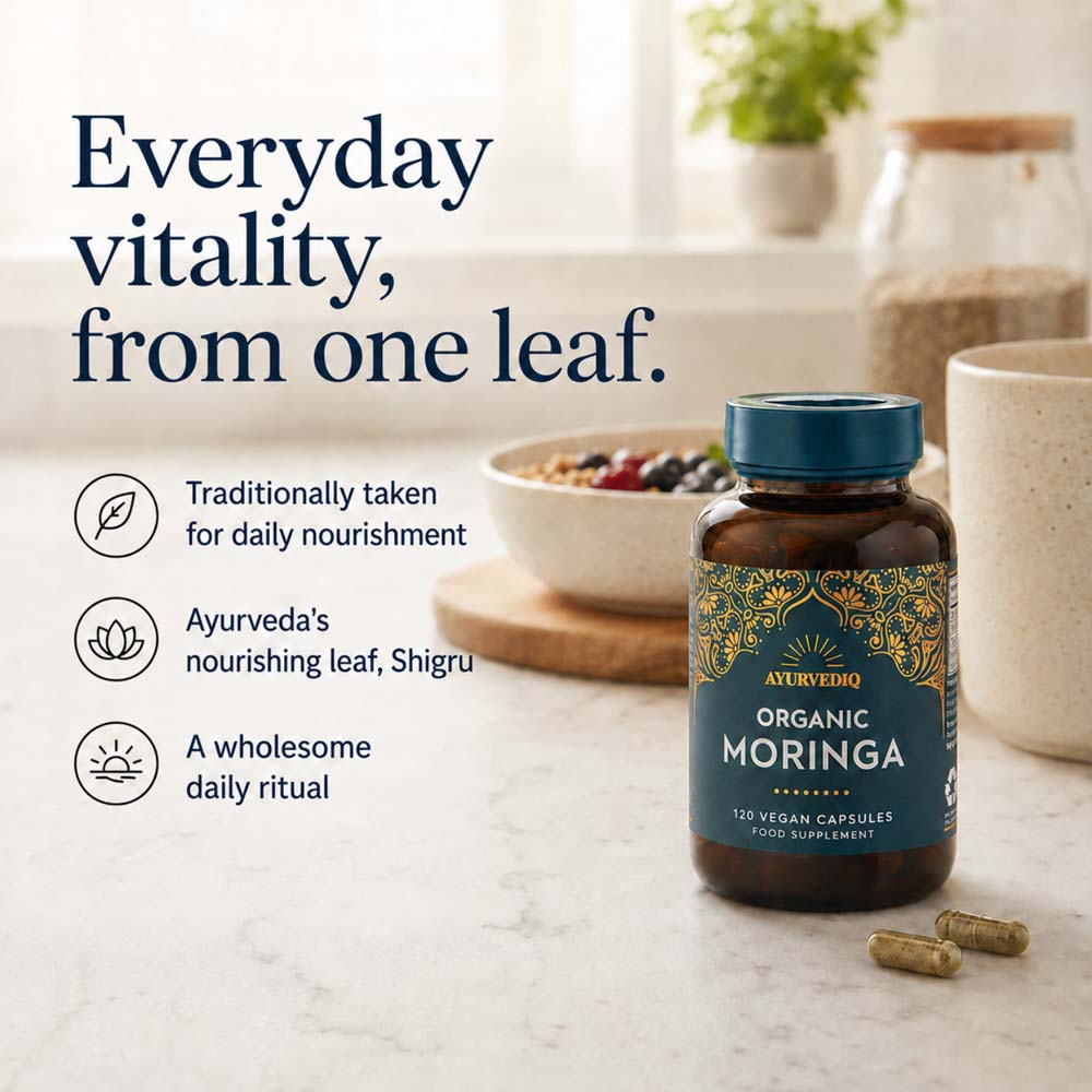 A bottle of Ayurvedic Organic Moringa capsules stands on a light countertop with two capsules