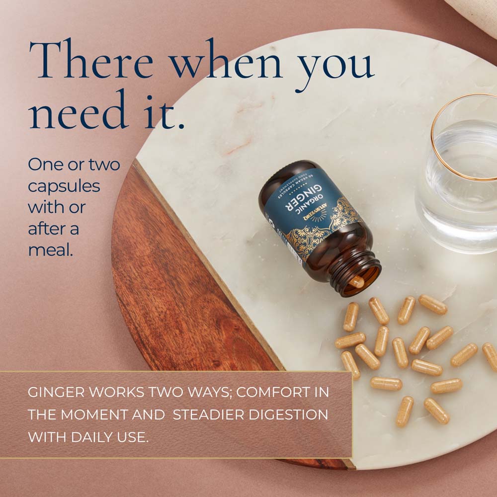 A bottle of ginger capsules lies on a white marble tray with scattered tan capsules beside it, alongside a glass of water. Large text reads, &