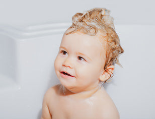 Baby in bath with shampoo in hair