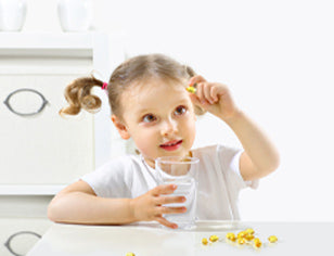 Young girl holding up omega capsule with a glass of water