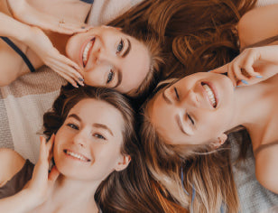 3 smiling girls lying down