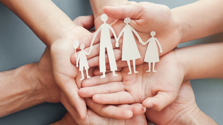 hands of a family holding a paper family cut out