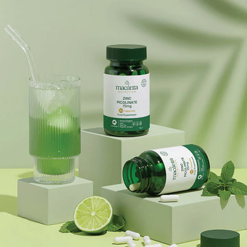 Green Macanta Zinc Picolinate supplement bottle with a glass of green juice and lime on a light green background
