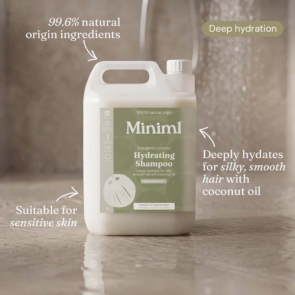 A large white plastic bottle of Minim1 Hydrating Shampoo with a sage green label, shown on a glossy tiled floor with marketing text callouts around it.