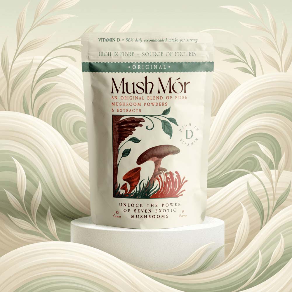 A stand-up pouch of Mush Mór mushroom powders and extracts centered on a white pedestal, with a decorative illustrated label showing mushrooms and botanical elements. The background is a soft, stylized cream and sage abstract floral pattern.