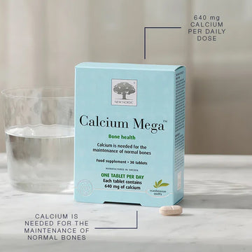 Box of Calcium Mega supplement with a glass of water on a neutral background