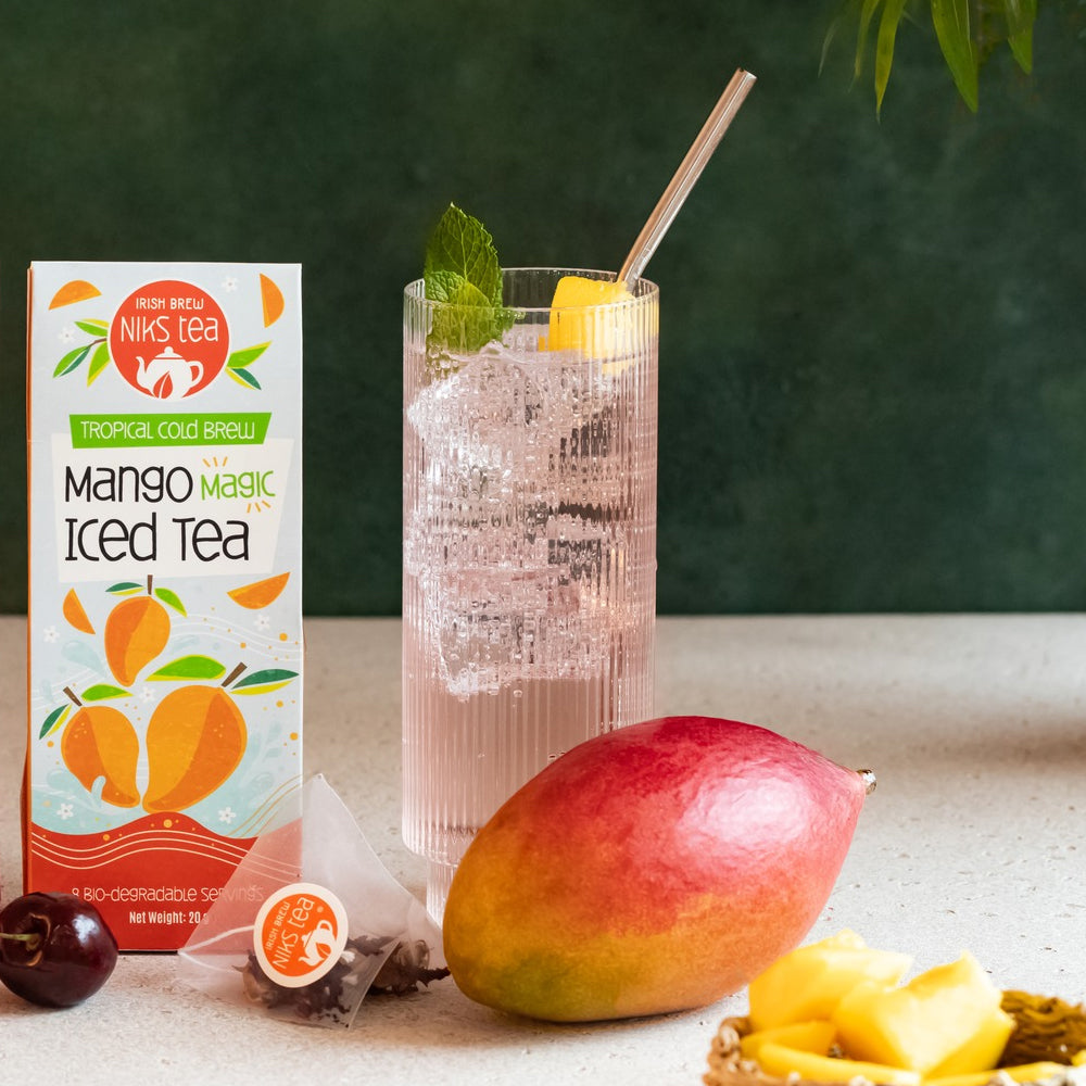 Mango iced tea packaging with a glass of iced tea and mango on a table.