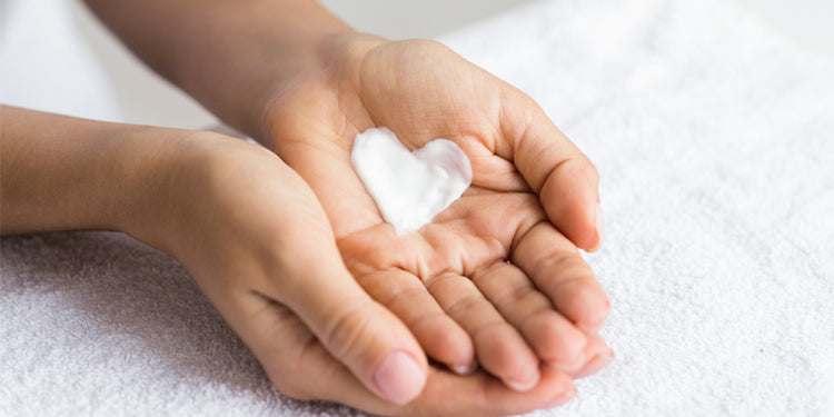 Cupped hands holding cream in the shape of a heart