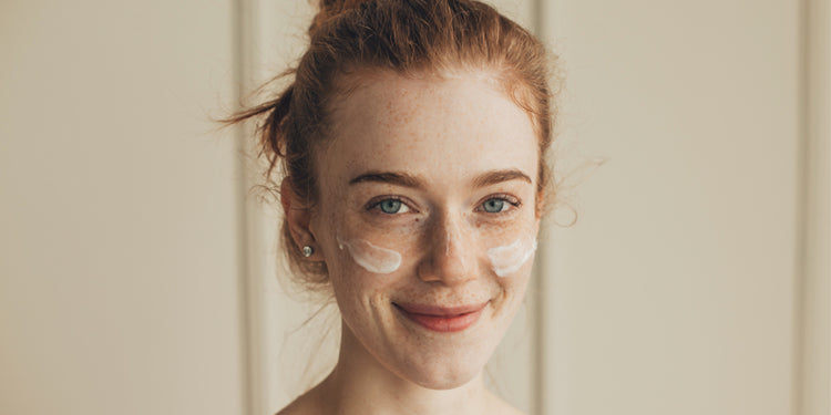 Smiling woman with red with eye cream