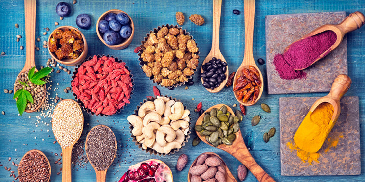 Selection of colourful superfoods on spoons on blue wooden background