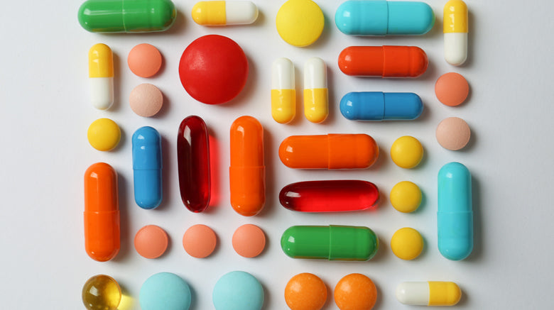 Colourful tables and capsules arranged on grey background