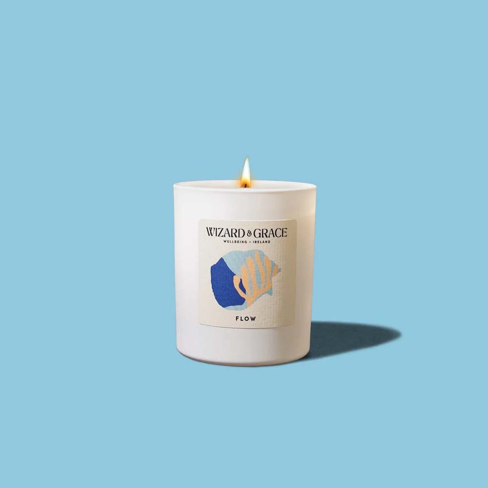 Lit Wizard & Grace "FLOW" natural candle in a matte white jar against a light blue background.