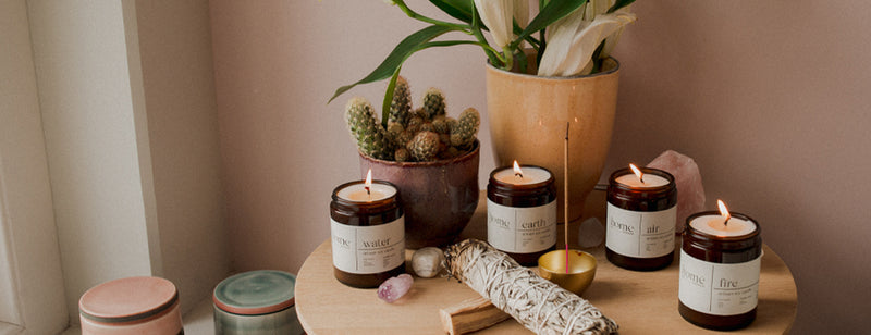 The Home Moment candles on wooden bench and plant