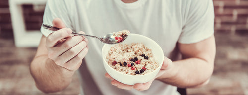 man eating bowl of porridge with berries as part of the glycaemic index diet to help with weight