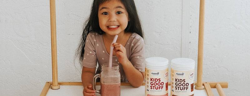 happy child drinking a smoothie with nuzest good kids stuff tub