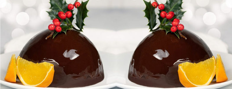 two glazed puddings with holly and orange slices