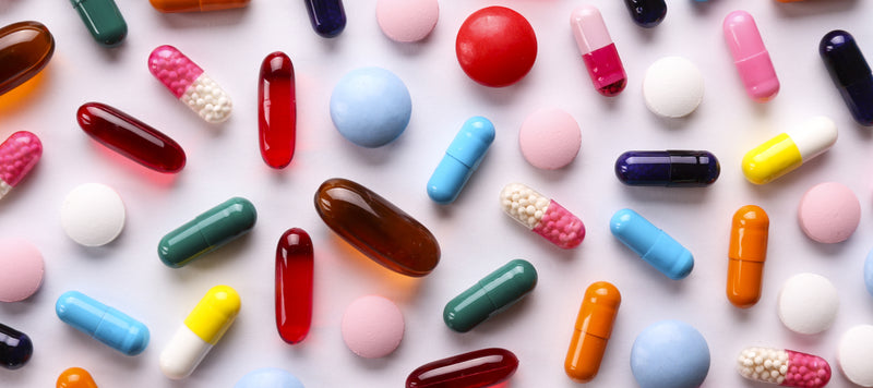colourful pills and capsules on a pink background