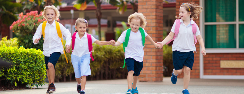 Four children running happily into school 