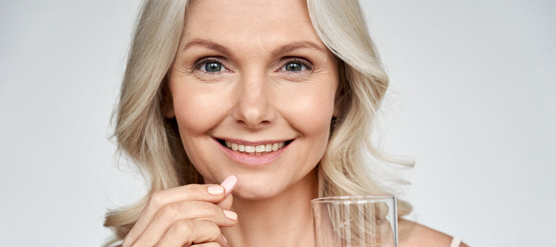 healthy woman with long grey hair taking a supplement
