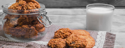glass jar with chewy banana oatmeal raisin cookies and a glass of milk