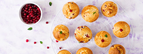 tray with cranberry and orange muffins beside a bowl of cranberries