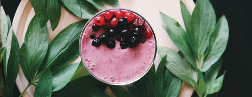 berry smoothie surrounded by green leaves