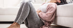woman sitting on the floor with cramping from IBS symptoms