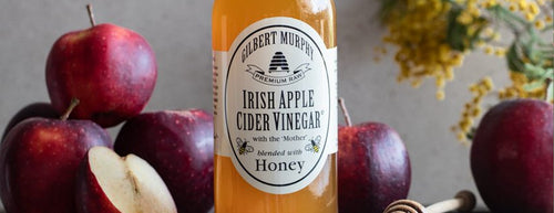 Bottle of Gilbert Murphy apple cider vinegar with freshly cut apples