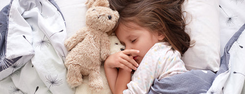 girl asleep with teddy in bed having a good night's sleep