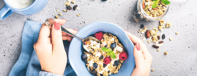 woman eating bowl of porridge with fruit as part of healthy breakfast habits