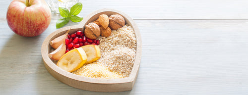 heart shaped bowl with heart healthy foods such as nuts, grains and garlic