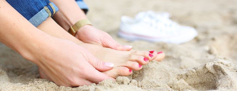 woman with summer ready feet sitting on the beach