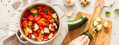 woman preparing healthy meal full of vegetables - important when it comes to managing stress with a healthy diet