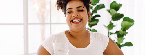smiling woman with healthy skin drinking a glass of water