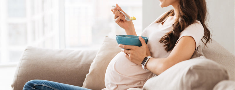 woman eating a healthy snack on the couch during pregnancy