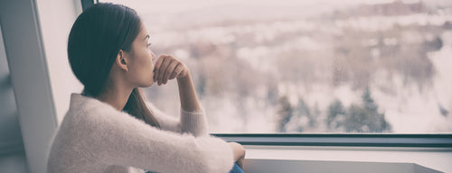 woman with seasonal affective disorder looking out the window in winter