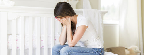 woman with postnatal depression sitting beside a cot