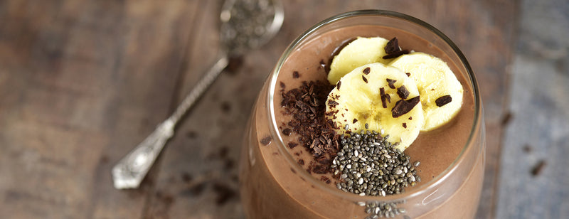 glass of protein-rich chocolate milkshake with banana and chia seeds on top