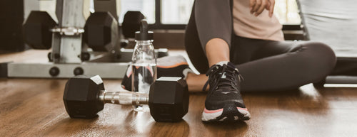 woman at the gym with dumbbell and water bottle 