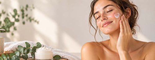 Woman gently applying moisturising cream to her face, surrounded by natural skincare essentials for a gentle winter skincare routine for sensitive skin.