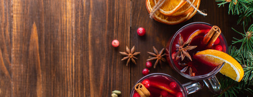 mugs of mulled wine with orange segments, cinnamon and star anise
