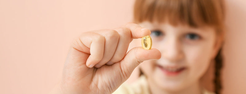 little girl holding up a multivitamin for kids