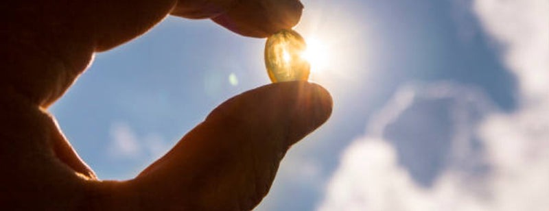 holding a vitamin d supplement up toward the sun