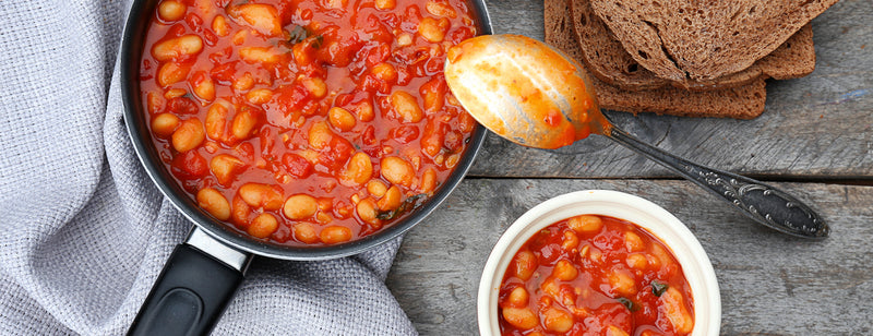 pan of tomato, vegetable and butter bean stew with bread brown