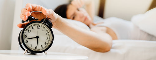 woman checking time on clock - trying to get your sleep cycle back on track